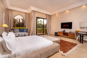 een slaapkamer met een bed, een tv en een bank bij Palais Nouhass in Marrakesh