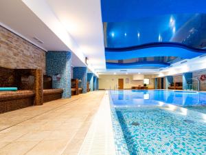 a large swimming pool in a hotel with a blue ceiling at Hotel Delfin Spa&Wellness in Dąbki