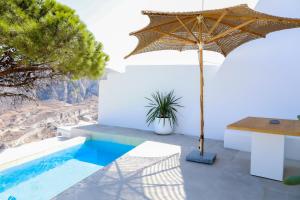 een patio met een parasol en een tafel bij Luna Santorini Suites in Pirgos