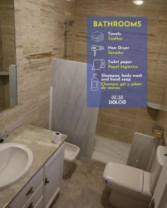 een badkamer met een wastafel, een toilet en een bord bij Retiros Dolca in La Marina de la Torre