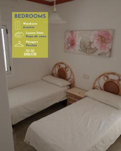 twee bedden in een kamer met een bord aan de muur bij Retiros Dolca in La Marina de la Torre
