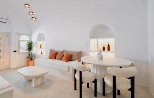 een woonkamer met een witte bank en een tafel en stoelen bij Luna Santorini Suites in Pirgos