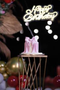 a pink cake with a bow on top of a table at Tranquil Farmstay by Vanaja Farms in Rāmanagaram