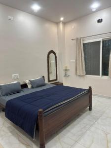 a bedroom with a bed with blue sheets and a mirror at Tranquil Farmstay by Vanaja Farms in Rāmanagaram +32 photos