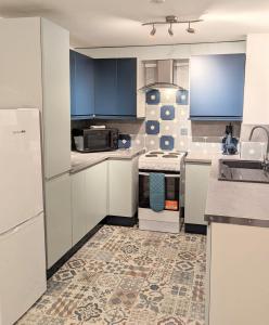 Una cocina con gabinetes blancos y piso de baldosas. en Fairway house, en Kilchenzie