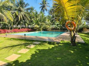 a swimming pool in a yard with a palm tree at Tranquil Farmstay by Vanaja Farms in Rāmanagaram
