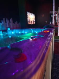 a bar with a pool in a room with purple lights at Suite love Jacuzzi in Charleroi