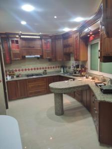 une grande cuisine avec des placards en bois et un plan de travail en granit. dans l'établissement Villa luxueuse, à El Guern