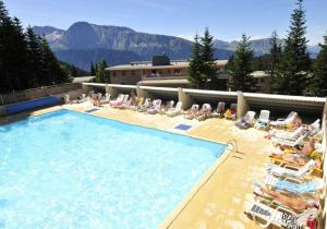 a group of people laying in chairs in a swimming pool at Le Manchot - Au pied des remontées mécaniques in Chamrousse