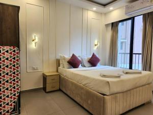 a bedroom with a large bed with purple pillows at Relaxed 1BHK Retreat - Pool, Balcony, Secure Parking, Walk to Candolim Beach in Candolim +22 photos