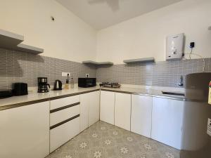 a large kitchen with white cabinets and appliances at Relaxed 1BHK Retreat - Pool, Balcony, Secure Parking, Walk to Candolim Beach in Candolim
