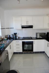 a kitchen with white cabinets and a stove top oven at Castleton Self-Catering Accommodation in Plettenberg Bay +11 photos