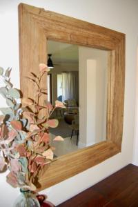 a mirror on a wall with a vase with a plant at Castleton Self-Catering Accommodation in Plettenberg Bay