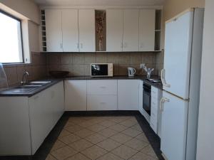 a kitchen with white cabinets and a sink and a refrigerator at Kaaimans Crest Sea-View Apartments - Great Brak River in Groot Brak Rivier