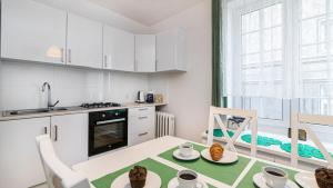 Una cocina con gabinetes blancos y una mesa y sillas. en Maya's - Duga 66, en Gdansk