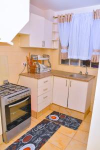 a kitchen with a stove and a kitchen rug on the floor at Genesis Grove BnB Syokimau in Syokimau