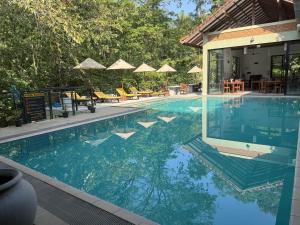 ein großer Swimmingpool mit Liegen und Sonnenschirmen in der Unterkunft Arika Villa in Dambulla + 37 Fotos