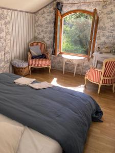 ein Schlafzimmer mit einem Bett und zwei Stühlen und einem Fenster in der Unterkunft Nuit entre mer et montagne in Caixas