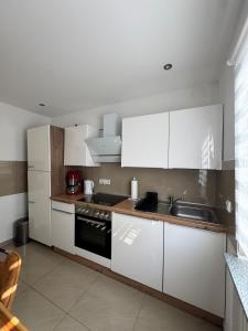 een keuken met witte kasten en een spoelbak bij Idyllische Wohnung mit Küche & Bad in Bielefeld in Bielefeld
