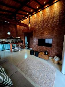 a living room with a brick wall with a flat screen tv at Casa na Rampa - Hospedagem no Caravaggio in Santa Teresa +14 photos