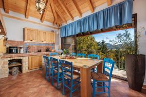 a kitchen with a wooden table and chairs and a large window at Hillside Lodge, Boutique & Spa in Lič