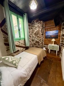 a bedroom with a bed and a stone wall at Meson el Acebo in El Acebo de San Miguel