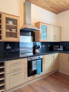 a kitchen with wooden cabinets and a stove top oven at Whisky Row in Campbeltown