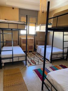 a room with three bunk beds and a rug at Mirleft Hostel in Mirleft