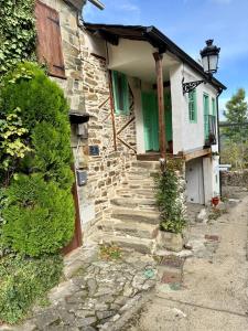 an old stone house with a green door and stairs at Meson el Acebo in El Acebo de San Miguel