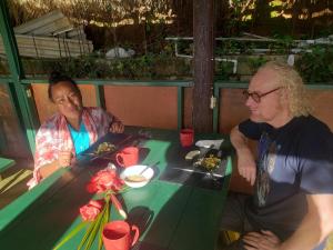 a man and a woman sitting at a table with food at Blue Mountain Wilderness Retreat Jamaica House in Port Antonio