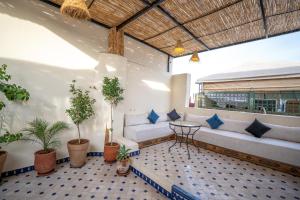 a balcony with a couch and a table and potted plants at Riad Dar Sira in Fès