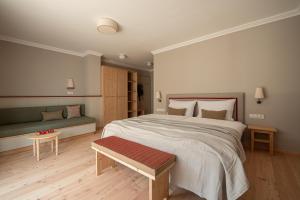 a bedroom with a large bed and a bench at Vitalpina Hotel Schulerhof in Plaus