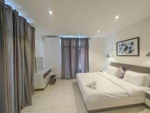 a bedroom with a large white bed and a window at Embassy Onebedroom by Unique Abodes in Accra