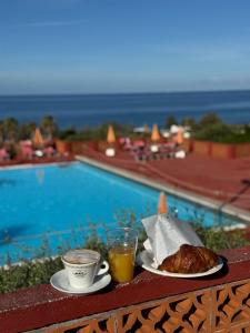 un petit-déjeuner composé de café et de croissants au bord de la piscine dans l'établissement Happy Camp Mobile Homes in El-Bahira Camping Village, à San Vito Lo Capo