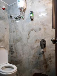 a bathroom with a toilet and a marble wall at Marquis Luxe Guest House in Kolkata