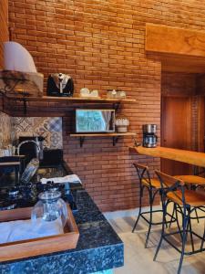 a kitchen with a brick wall and a counter with chairs at Casa na Rampa - Hospedagem no Caravaggio in Santa Teresa
