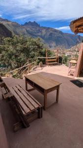 a wooden table and bench on a patio with mountains at Sevawasi in Cusco +4 photos