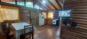eine Küche mit einem Kühlschrank und einem TV in einer Hütte in der Unterkunft cabaña en el bosque in Valle Hermoso