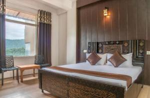 a bedroom with a large bed and a window at Suffer Heights Kasauli I Vacations I Family Groups & Events I Forest Treks I Memories Toy Train View I Serviced Apartments I Kasauli By Exotic Stays in Kasauli