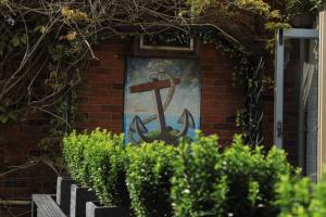 an anchor painted on the side of a building with bushes at The Blue Anchor in Feering