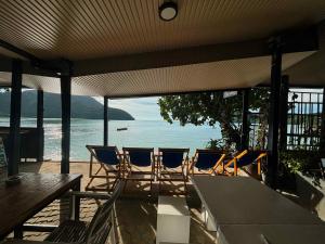 a patio with chairs and a table and a view of the ocean at The One Hostel Phi Phi Island in Phi Phi Don
