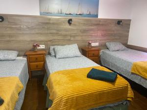 a room with three beds with yellow and gray blankets at El Rincon del Rey in Torrejón del Rey