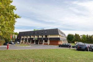 a building with cars parked in a parking lot at ibis Styles Parc des Expositions de Villepinte in Villepinte