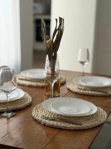 a wooden table with three plates and a vase with flowers at Andina Apart - Calm in the heart of Mendoza in Mendoza