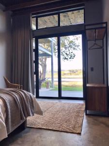 een slaapkamer met een bed en een grote glazen deur bij Bellevue on the Knysna lagoon in Knysna