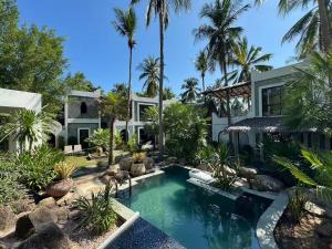 an exterior view of a house with a swimming pool and palm trees at Shanti Rock Residence Koh Phangan in Ko Kong Nui