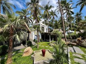 a white house with palm trees and a red vase at Shanti Rock Residence Koh Phangan in Ko Kong Nui