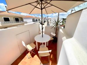 ein Balkon mit Tisch und Stühlen und einem Sonnenschirm in der Unterkunft Casa Tété in Benagil