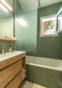 a bathroom with a sink and a tub and a window at Gîte des pins in Sainte-Marie-de-Ré