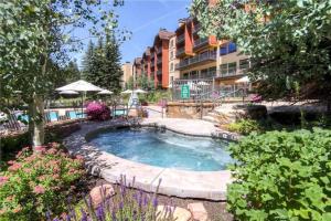 une piscine dans une cour avec un bâtiment dans l'établissement Ski In, Ski Out Studio Condo In The Heart Of Lionshead Village With Mountain View, Hot Tubs, And Pool Access, à Vail